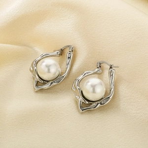 Detail of irregular textured silver earrings featuring a lustrous pearl on silk fabric