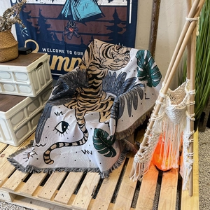 Close-up of bohemian tiger pattern woven blanket with decorative fringes in a camping setup