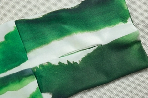 Detail of sleeve cuff with thumbhole design and green abstract ink print fabric