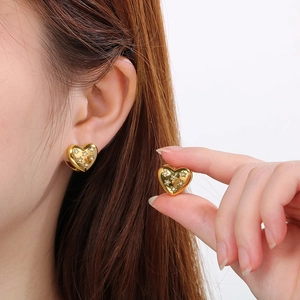 Close-up of gold heart earrings with sparkling star-shaped crystal inlays on a model