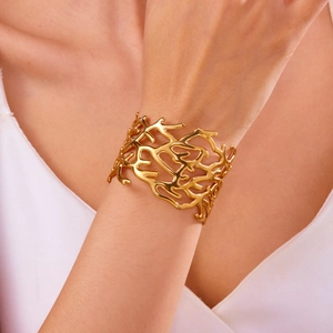 Detailed view of wide gold coral texture cuff bracelet worn on a woman wrist