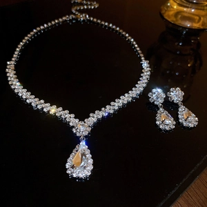 Elegant silver zircon jewelry set with Y-shaped necklace and teardrop earrings on black reflection