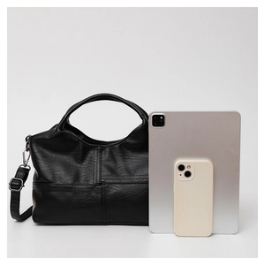 Detail showing soft black leather handbag capacity with tablet and phone for scale