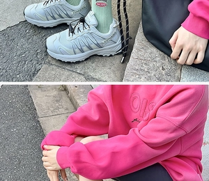 Close-up of gray athletic sneakers and bright pink hoodie with embossed lettering