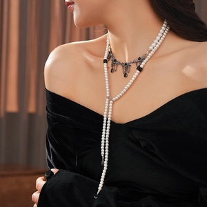 Detail of gothic double-layer pearl necklace with black droplet pendant on black velvet