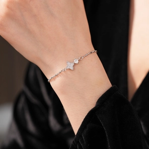 Gros plan d'un bracelet trèfle argenté serti de zircons brillants porté au poignet