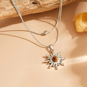 Détail du collier double chaîne serpent argentée avec pendentif soleil et pierre œil de chat