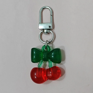 Detailed view of red resin cherry keychain with green bow and silver metal clasp