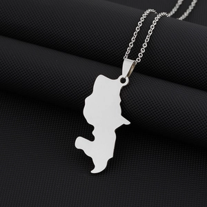 Close-up of a silver Martinique map pendant necklace on a black textured surface