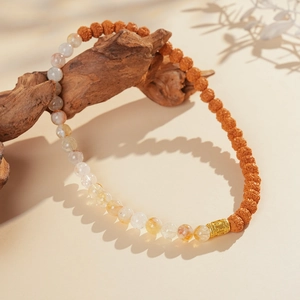 Macro detail of yellow rutilated quartz and rudraksha seeds on a rustic wood branch