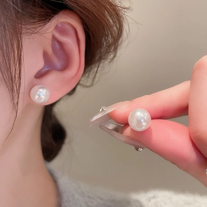 Close-up of elegant round pearl stud earrings worn by a model for a chic look