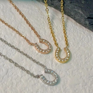 Detailed view of horseshoe pendants in gold, silver, and rose gold with zircon inlay