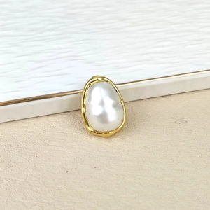 Detailed macro view of a baroque freshwater pearl with a textured gold plated metal border