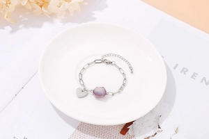 Detail of silver chain bracelet with purple hexagonal bead and small heart charm