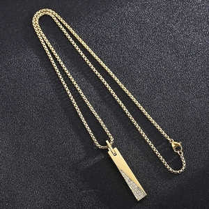 Detailed close-up of golden bar pendant necklace with diagonal crystal rhinestones