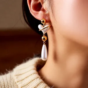 Vintage French style gold earrings with pearl heart pendants worn by a female model
