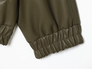 Detailed view of dark green faux leather jacket cuff with elastic ribbed hem and stitching