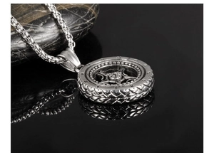 Macro detail of silver tire-shaped pendant with gothic star motif on a round link chain