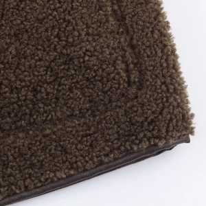 Macro detail of dark brown sherpa fleece fabric with premium faux leather binding trim