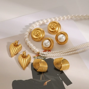 Retro jewelry set with gold floral earrings and white pearl necklace on art magazine