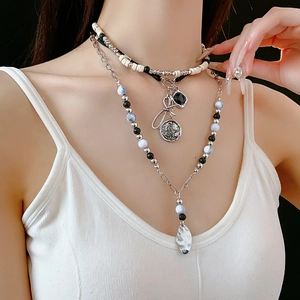 Close-up of layered beaded bow necklace with silver charms and vintage coin pendants
