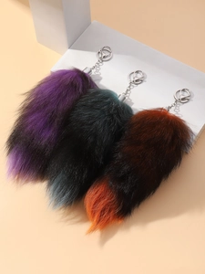 Close-up of fluffy faux fox tail keychains in purple, green, and orange gradient fur