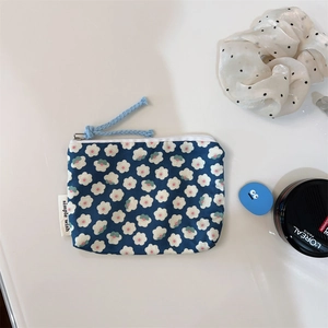 Close-up of small floral cotton coin purse with blue zipper pull and side label detail