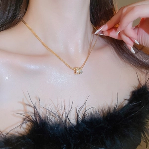 Detail of layered gold-plated necklace with zircon cylinder pendant worn by model