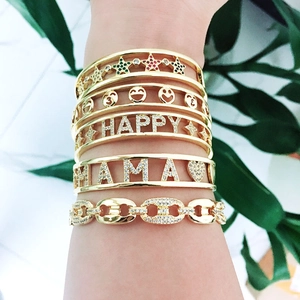 Detail of layered gold Mama and Happy bracelets with zircon stars and chunky chain links