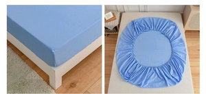 Detail of blue fitted sheet corner stitching and elastic edge on a modern bed