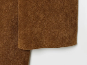 Vista macro dettagliata della texture scamosciata marrone scuro su elegante cappotto da donna