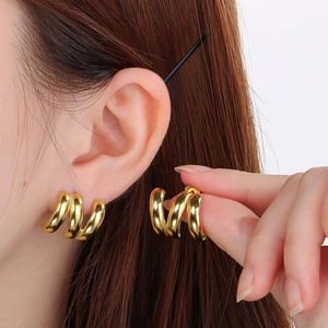 Close-up of three-layer gold spiral hoop earrings on model showing minimalist style