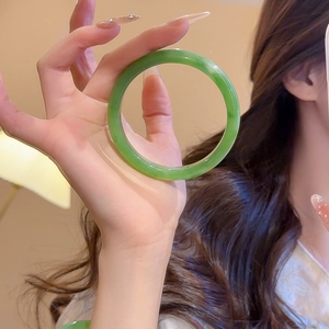 Detailed macro view of a polished green resin bangle featuring a traditional round profile