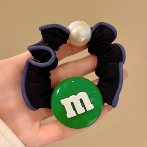 Détail d'un chouchou en tissu avec pendentif m vert et perle blanche décorative