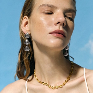 Elegant shell-shaped 18k gold pendant necklace and silver earrings set worn by a model
