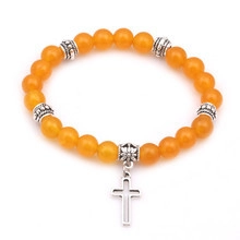 Vista dettagliata delle perle di corniola arancione e ciondolo a croce d'argento sul bracciale