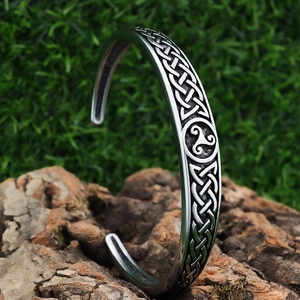 Vintage stainless steel twisted cuff bracelet with Celtic knots on a natural bark backdrop