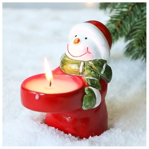 Detail of snowman candle holder with a burning tea light candle for Christmas decor