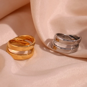 Detailed close-up of 18K gold and silver double-layered crisscross rings on silk