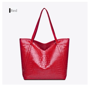 Detail of red crocodile texture tote bag with glossy finish and long shoulder straps