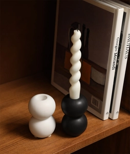 Minimalist ceramic candle holder set in black and white with spiral candle on a bookshelf