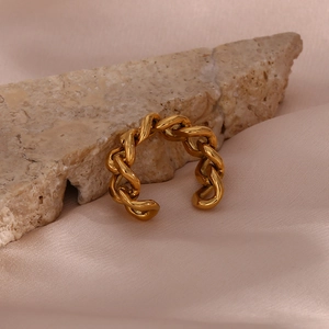 Detailed close-up of a golden Cuban link woven open ring on a pink silk background