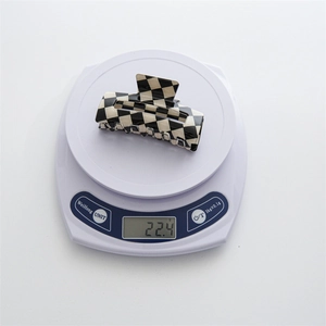 Detailed scale view showing the lightweight 22.4g checkerboard hair claw clip