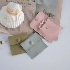 Detail of velvet envelope jewelry pouches in pink, green and blue with snap closure