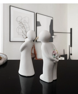 Detailed close-up of white ceramic couple figurines with matte texture and tiny flowers