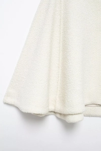 Close-up of elegant white blended wool-blend cape coat showing textured tweed fabric