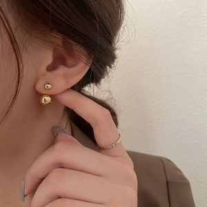 Close-up of elegant gold double ball earrings featuring a polished mirror finish on model