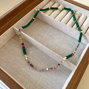 Macro view of gold-plated shell and pearl necklace with green beads in a wooden jewelry box