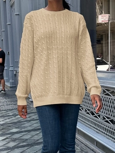 Detailed close-up of a beige cable knit sweater with textured patterns and ribbed cuffs