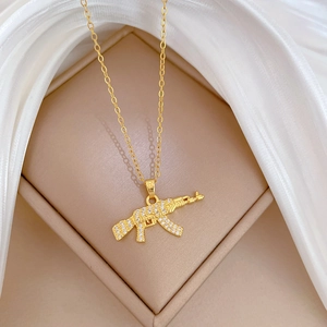Detailed close-up of a sparkling crystal-encrusted rifle pendant on a gold necklace